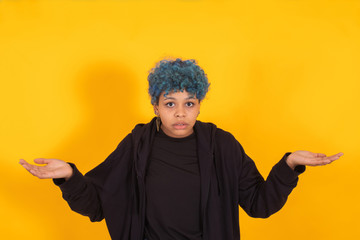 young african american girl or woman with blue hair isolated on yellow background