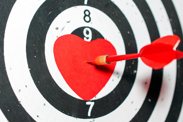 Darts board with a red heart on the target, dart hitting the target. Valentine's day concept
