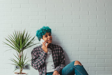 young modern african american girl with blue hair and mobile phone in the apartment