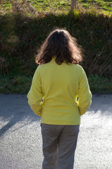 enfant de dosavec vetement jaune  boudant. child from behind with sulky yellow clothing.