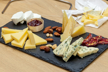 A cheese cutting from different types of cheese on a wooden board