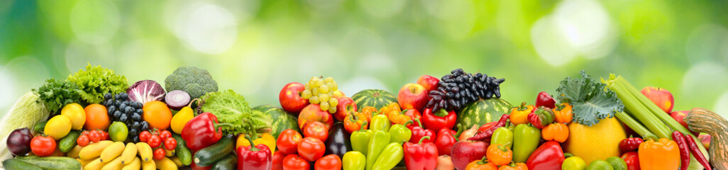 Panorama multicolored fresh fruits and vegetables on green background.