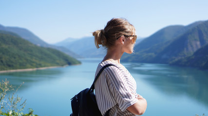 Smiling woman against mountain landscape and lake. Zhinvali reservoir lake landscape with mountains...