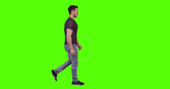 Man walking and looking around the street, waving and reacting to pedestrians and to the camera, over green screen.