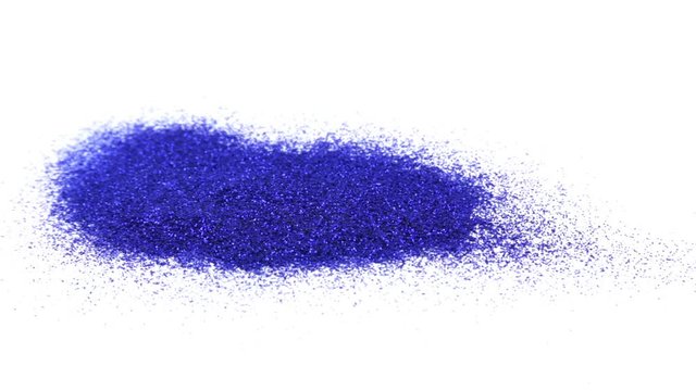 Falling blue glitter dust. Blue sparkles fall to a pile on a white background