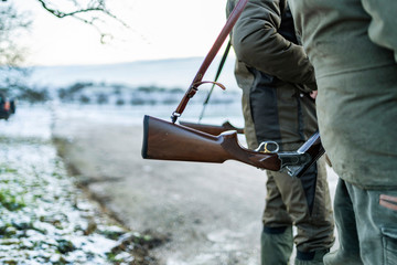 Detail view of hunters rifle. Hunter / gamekeeper in a field during winter day.