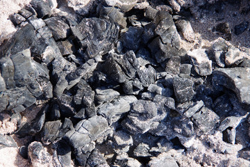 Close-up view of burned charcoal in an abandoned fire pit on the beach