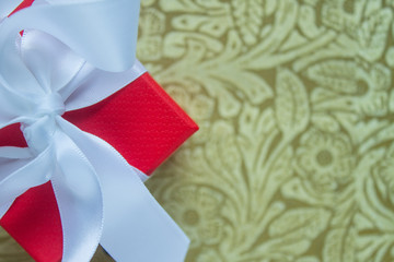 Red cardboard gift box with white satin bow on patterned texture background with copy space