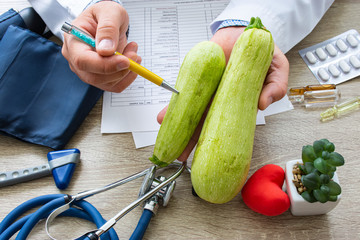 Doctor nutritionist during consultation held in his hand and shows patient squash or zucchini....
