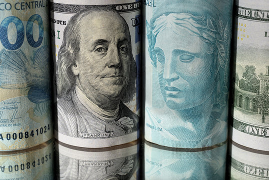 Notas de Cem Reais intercaladas com notas de Cem D&oacute;lares em rolos
