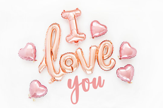 Pale pink Foil Balloons in the shape of the word "I Love You" with hearts on white background. Love concept. Holiday, celebration. Valentine's Day or wedding/bachelorette party decoration.