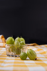 Small glass cup overfilled cherry-cherry-plums. Black background.