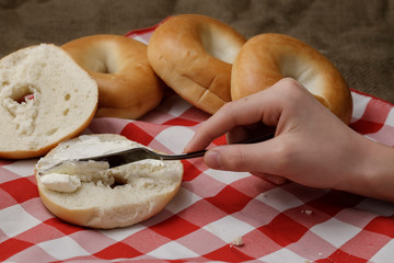Spreading cream cheese on a bagel.