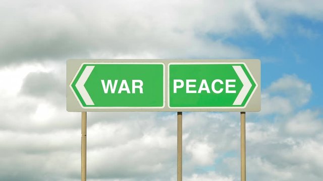 Pointing the way in opposite directions to war or peace on a road sign with timelapse white clouds in the background. Taking the road to war or peace.