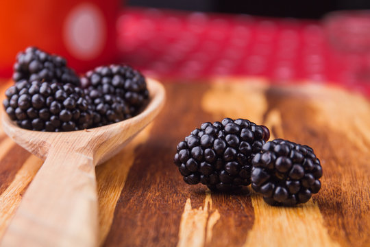 Two focused blackberries, close-up. Rural wooden tablespoon with berries.
