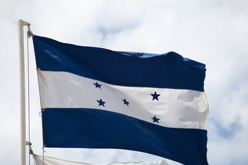 Fototapeta na wymiar Flag of Honduras waving against cloudy sky