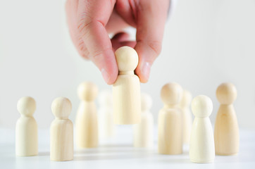 Hand of a businessman choosing wooden figure in conceptual image of search, hiring, business...
