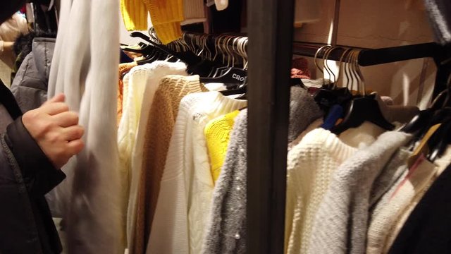 The buyer chooses a sweater in the mall.