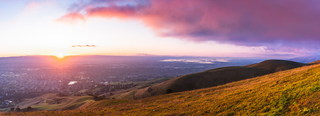 Fototapeta na wymiar Panoramic sunset view of San Jose and South San Francisco Bay Area, also known as Silicon Valley; hills starting to turn green visible in the foreground; California