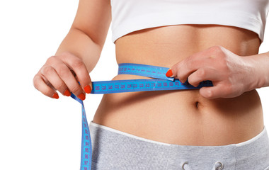 a young slender woman measures her waist with a centimeter tape. isolated on white background