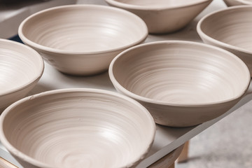 raw ceramic bowls made from white clay on the potter's wheel circle waiting for putting in the pottery kiln, concept of manual work, creativity and art, vertical photo