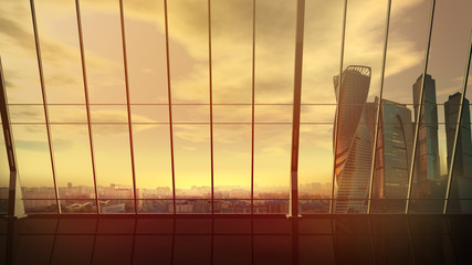 Empty office with view of cityscape with skyscrapers at sunset.