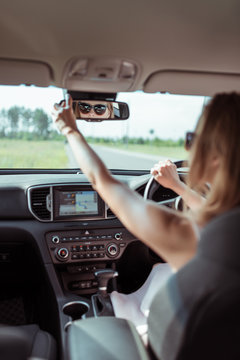 A woman driving a car, looking in the rearview mirror, reversing, parking at a shopping center, driving a car into the garage. Automatic transmission. Vehicle interior. Summer girl in a dress.