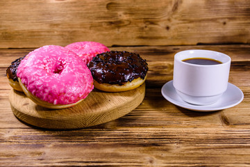 Cutting board with glazed donuts and cup of coffee on a wooden table