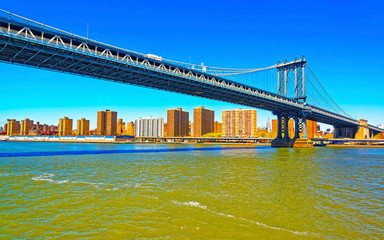 Obraz premium Manhattan bridge across East River, New York, USA. It is among the oldest in the United States of America. NYC, US. Skyline and cityscape. American construction