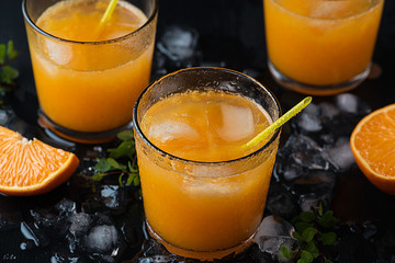 Tangerine cocktails with sliced mandarins, ice, mint on a black wooden table