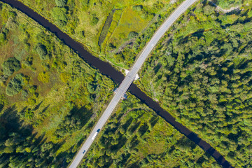 The time of year is summer. Road through a country of pine forests and lakes aerial view