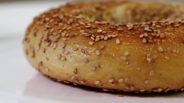 Bagel with seeds on plate moving from left to right