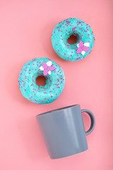 Blue Donuts with icing and coffe cup on pastel rose background. Sweet donuts.