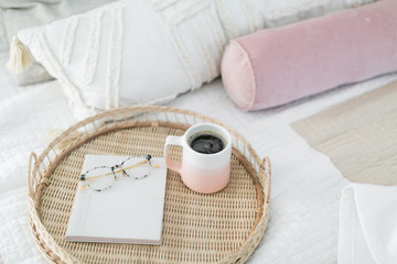 Coffee in pink mug, notebook, and glasses on tray sitting on bed, coffee in bed, pink bedroom decor
