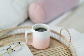 Coffee in pink mug, notebook, and glasses on tray sitting on bed, coffee in bed, pink bedroom decor