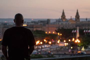 A man looks out over the ancient city of Valletta in the Mediterranean capital city of the island nation of Malta. - obrazy, fototapety, plakaty