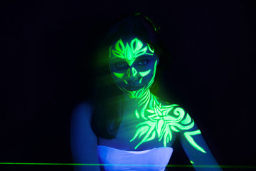 Body art on the body and hand of a girl glowing in the ultraviolet light.