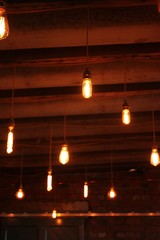 Hanging glowing warm light lightbulbs from rustic wood ceiling indoors