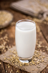 Portion of healthy Oat Milk on an old wooden table (selective focus; close-up shot)