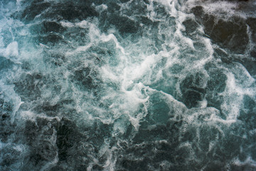 Raging blue water in a backwater with stones and white foam.