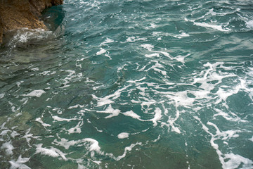Naklejka premium Raging blue water in a backwater with stones and white foam.