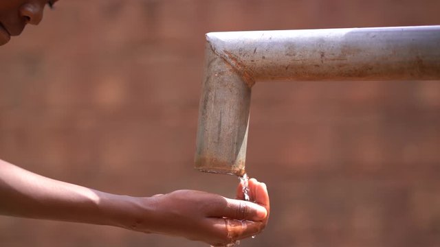 Close Up of a Girl's Hand Reaching Out For Water At the Village Pump Station