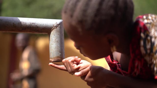African Girl Counting Drops At A Drying Out Water Pump Station