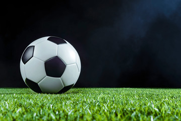 Soccer ball on green field at night with floodlight