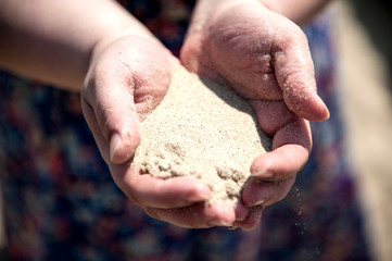 The girl holds in hands a light sea sand.