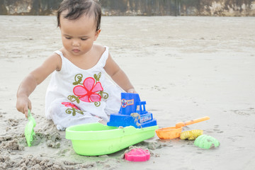 Little girl playing sand alone at the beach.