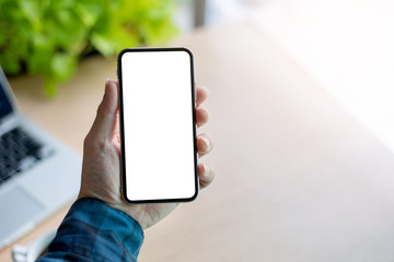 Mockup image blank white screen cell phone.man hand holding texting using mobile on desk at office.background empty space for advertise text.people contact marketing business,technology 