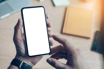 Mockup image blank white screen cell phone.man hand holding texting using mobile on desk at coffee shop.background empty space for advertise text.people contact marketing business,technology 