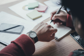 looking at luxury watch on hand check the time writing business information in notepad at...