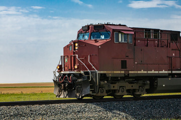 Vintage locomotive of a red Canadian National Railways vintage freight train, with headlights on, moving towards left. Copy space on the left.